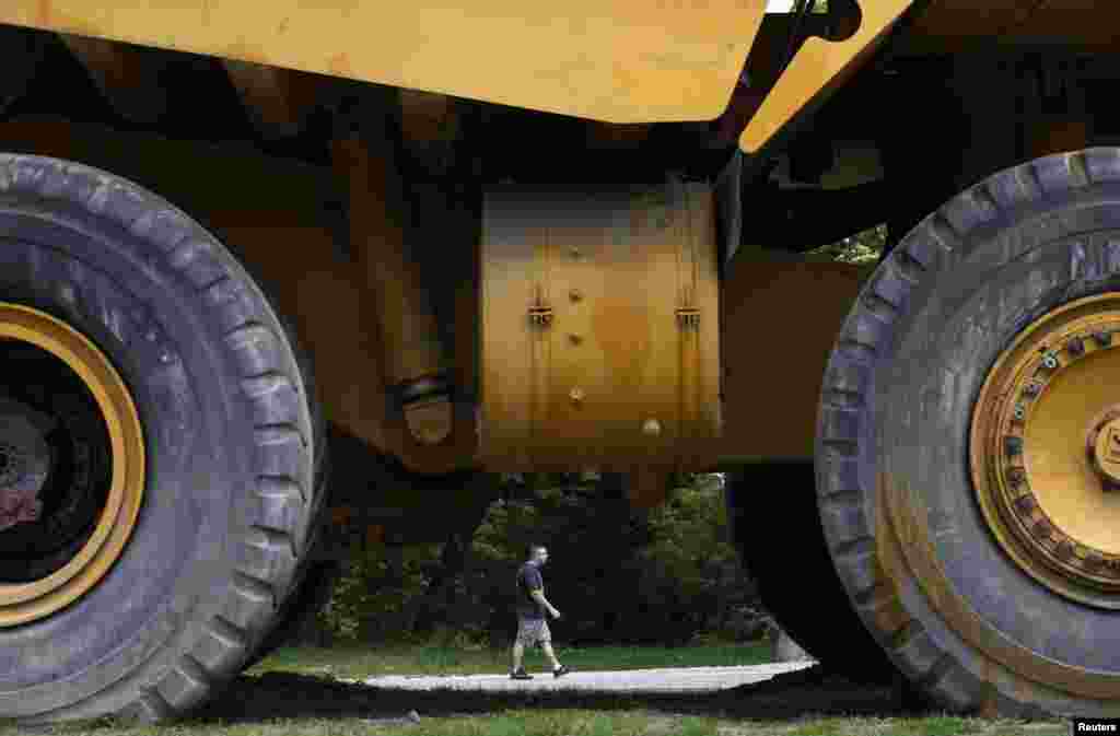 A man passes by an old dump truck used in mining operations.