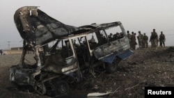 Afghan security force inspect the wreckage of a bus hit by a suicide car-bomb attack in Kandahar Province on July 2