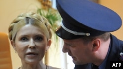 A police officer tries to calm Yulia Tymoshenko as she reacts to the verdict.