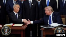 Вице-премьер Госсовета Китая Лю Хэ (слева) и президент США Дональд Трамп обмениваются рукопожатием на церемонии подписания соглашения о первой фазе торгово-экономической сделки. Белый дом, Вашингтон, 15 января 2020 года.
