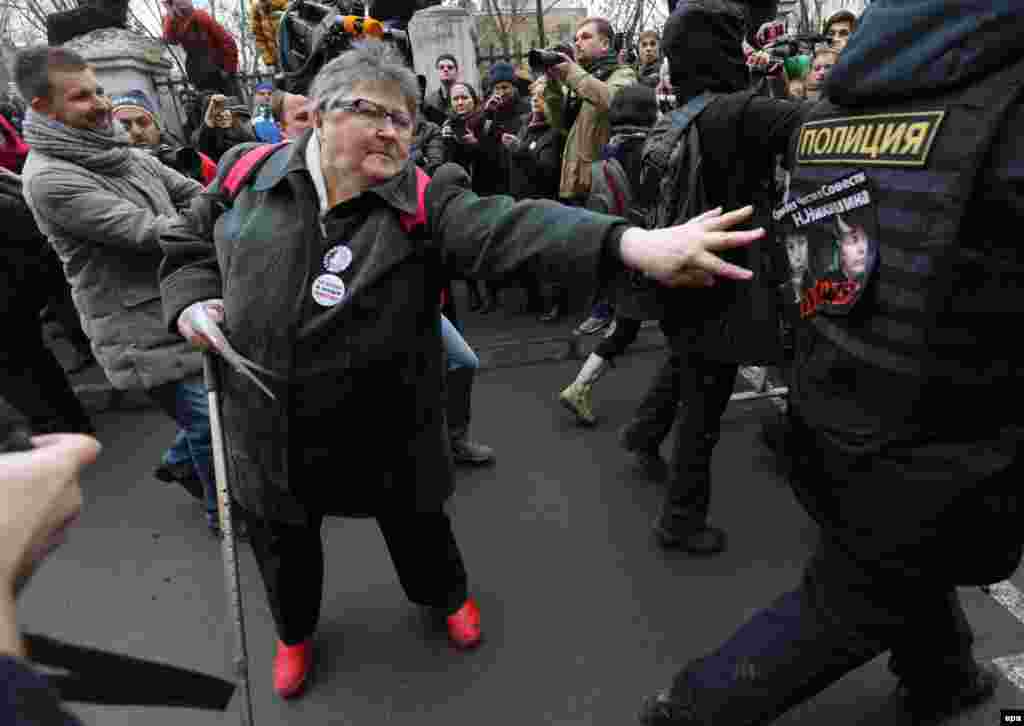 An elderly woman fixes to a policeman's vest a leaflet, reading "Judge without honor and conscience" and showing a portrait of a judge engaged in the Bolotnaya case during a support action in front of Zamoskvoretsky district court in Moscow. (epa/Sergei Chirikov)
