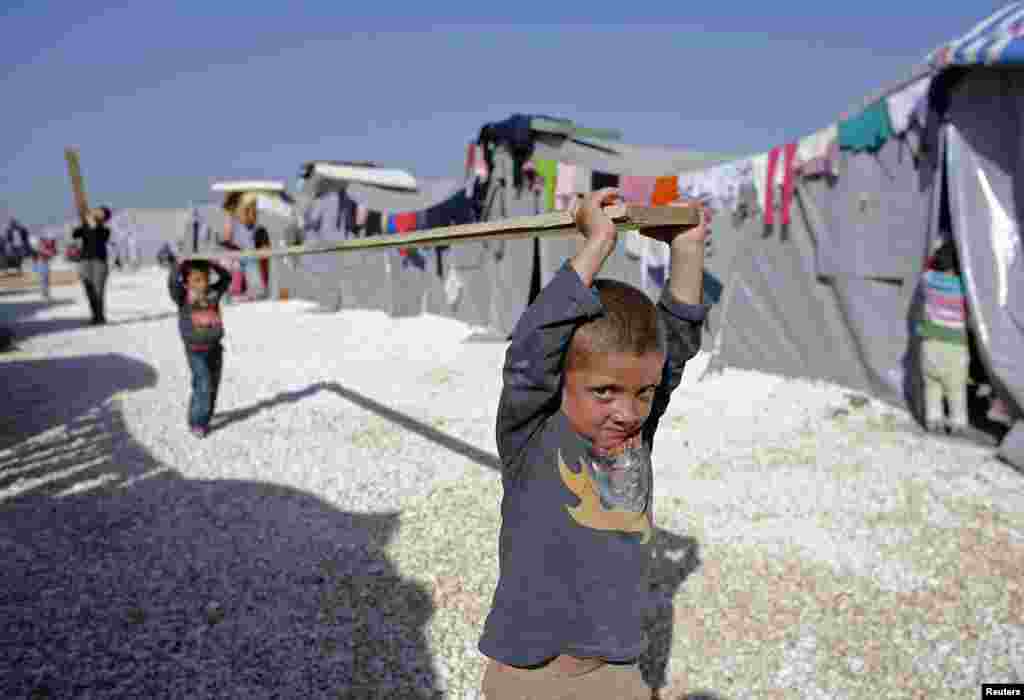 Kurdish refugee boys from the Syrian town of Kobani carry a wooden beam in a refugee camp near the Turkish border town of Suruc. (Reuters/Osman Orsal)