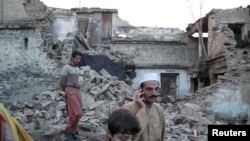 Residents walk past the rubble of a house after it was damaged by an earthquake in Mingora, Swat on October 26.