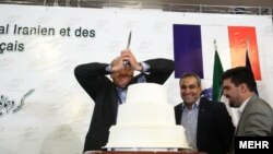 یکی از اعضای هیئت تجاری فرانسه در اتاق بازرگانی تهران، کیک مراسم همنشینی فعالان اقتصادی ایران و فرانسه را می‌برد