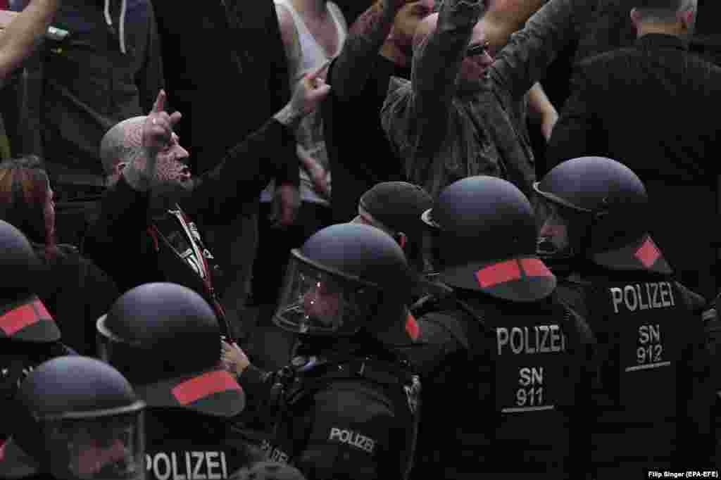 Right-wing protesters gesture toward police in riot gear as they gather at the place where a man was stabbed in the night of August 25 in eastern German city of Chemnitz. A 35-year-old man was reportedly stabbed and killed after what police described as a &quot;scuffle between members of different nationalities&quot; at a city festival. (EPA-EFE/Filip Singer)