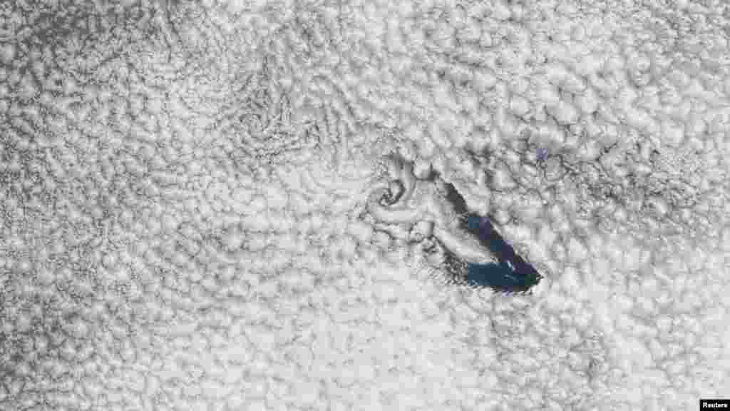 A NASA imaging spectroradiometer aboard an orbiting satellite captured this true-color image of St. Helena Island and a band of wind-blown cloud vortices trailing toward the island's leeward side over the South Atlantic Ocean. Tiny St. Helena lies approximately 1,900 kilometers west of Africa. (Reuters/NASA)