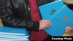 Казахстанский студент, держащий дипломную работу. Иллюстративное фото