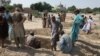 Pakistani mourners dig graves for the victims of a suicide blast outside the Sufi shrine in Jhal Magsi.