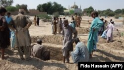 Pakistani mourners dig graves for the victims of a suicide blast outside the Sufi shrine in Jhal Magsi.