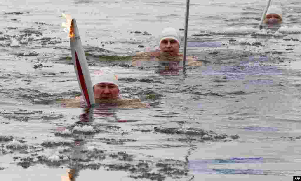 Olympic torchbearer Aleksandr Brylin (left) swims with his torch in the company of other ice-swimmers in the Amur River in the Far Eastern Russian city of Blagoveshchensk. Russia is hosting the Winter Olympics in the Caucasus city of Sochi in 2014. (AFP)