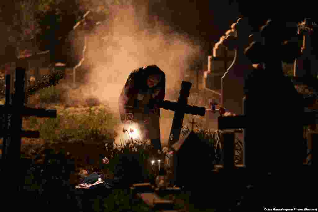 A woman burns incense near the grave of departed relatives in a cemetery outside the Romanian capital, Bucharest, on April 25. (Inquam Photos/Octav Ganea)