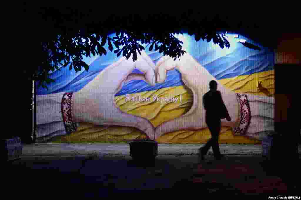 A local resident walks past a mural declaring, "I love Ukraine!" 