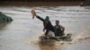 A motorboat carrying volunteers in Aq Qala in northern Iran during flood. A man is showing others he is bringing bread. March 27, 2019