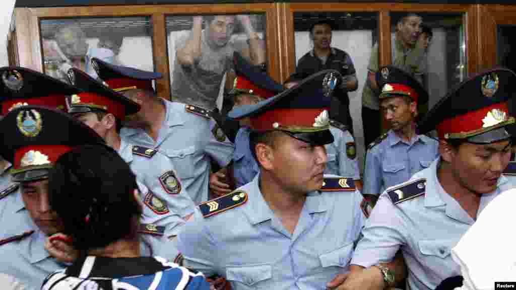 Defendants accused of participating in the December 2011 clashes in the Kazakh oil town of Zhanaozen react behind a glass barrier while Interior Ministry officers block the audience during a court session in Aktau on June 4. Relatives of 37 protesters accused of rioting in Zhanaozen crammed into a makeshift courtroom to await the verdicts in the largest trial relating to the deadly clashes. (Reuters/Olga Yaroslavskaya)