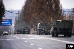 Trucks without license plates tow a 122mm Howitzer artillery piece through the rebel-held town of Makiivka, near Donetsk, on November 10.