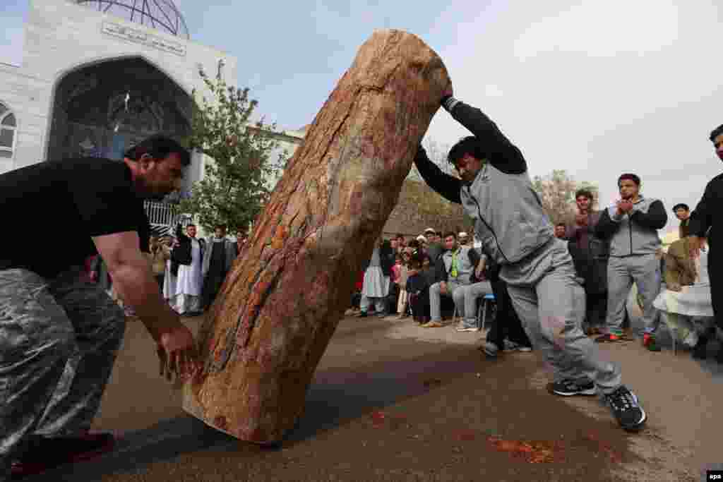 An Afghan athlete raises a tree-trunk during a strongman contest in Herat on November 8. (epa/Jalil Rezayee)