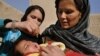 An Afghan woman holds a child as a health worker administers a polio vaccine. Polio-eradication can be dangerous work in some parts of Afghanistan, because some religious extremists have condemned it. 