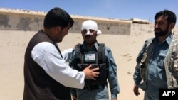 FILE: A wounded Afghan policeman stands guard at site of a suicide bomb attack in Zabul, May 2015.