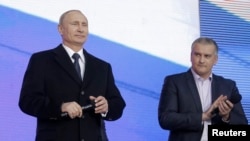 Russia - Russian President Vladimir Putin (L) and Crimean Prime Minister Sergei Aksyonov attend a festive concert marking the first anniversary of the Crimean treaty signing in central Moscow, March 18, 2015