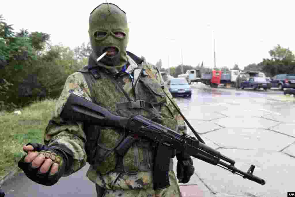 A Pro-Russian separatist fighter holds a grenade as he stands guard at a checkpoint on a road near the Donetsk airport. (AFP/Philippe Desmazes)