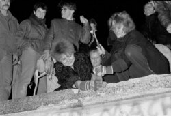 Берлинцы на стене, которая перестала разделять их город. 9 ноября 1989 года
