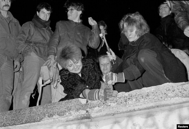 Німеччина. Берлінці молотком і зубилом розбивають ділянки Берлінської стіни перед Бранденбурзькими воротами після оголошення про відкриття східнонімецького кордону в Берліні, 9 листопада 1989 року