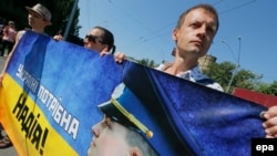Ukrainian activists hold a banner with a slogan reading "Ukraine needs Nadiya" and a Nadiya Savchenko portrait during a rally in front of the Russian Embassy in Kyiv demanding her release.