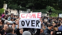 A demonstrator holds a sign reading "Game Over" during a rally in front of the Interior Ministry in Tunis on January 14.