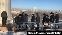 Азаматтық белсенділер мемлекеттік ту ілінген флагшток түбіне гүл қойып жатыр. Астана, 16 желтоқсан 2017 жыл.