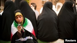 Ұялыбайланыс телефонын қарап отырған ирандық әйел. Тегеран, 16 маусым 2009 жыл.