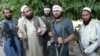 Taliban militants stand with residents as they took to the street to celebrate the cease-fire on the second day of Eid in the outskirts of Jalalabad on June 16.