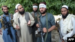 Taliban militants stand with residents as they took to the street to celebrate the cease-fire on the second day of Eid in the outskirts of Jalalabad on June 16.