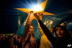 Participanți la un miting de Ziua Europei la București, pe 9 mai, luminează cu telefoanele mobile stelele unui imens steag al Uniunii Europene