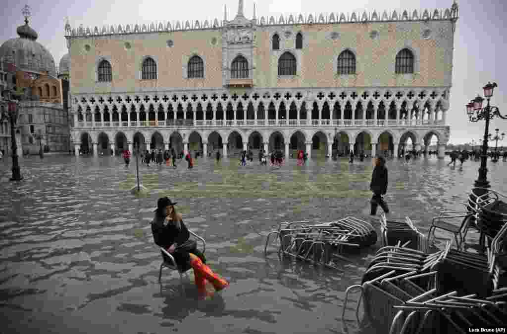 A woman sits in a chair in a flooded St. Mark&#39;s Square in Venice. The high-water mark hit 187 centimeters, meaning more than 85 percent of the city was flooded. The highest level ever recorded was 194 centimeters during infamous flooding in 1966. (AP/Luca Bruno)