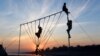 PAKISTAN -- Pakistani children play on crossbar swings at sunset in Lahore, January 9, 2019