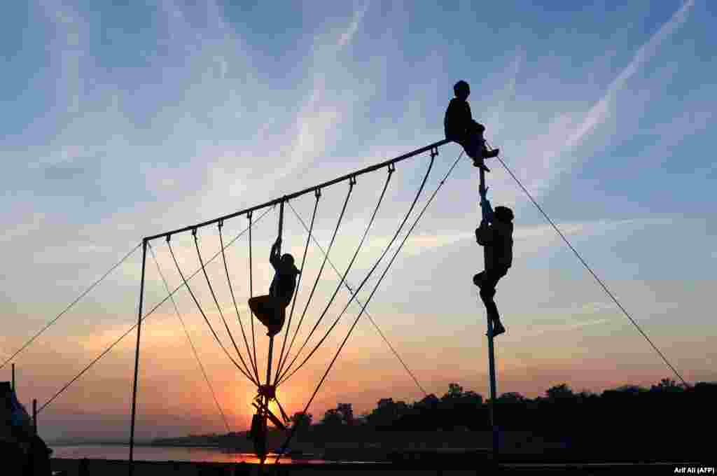 Pakistani children play on swings at sunset in Lahore. (AFP/Arif Ali)