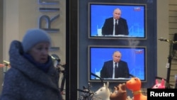 Кишилер Омскидеги ресторанда тамактанып жатышат. Телевизордун экранында Москвадагы Орусиянын президенти Владимир Путиндин маалымат жыйыны түз көрсөтүлүүдө. 2023-жыл, 14-декабрь