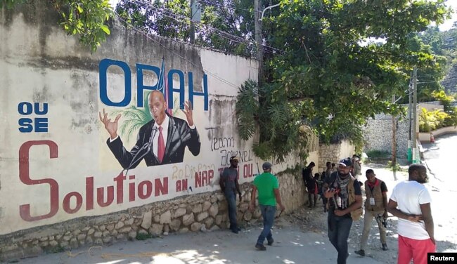 Ljudi prolaze pored zida na kojem je prikazan predsednik Haitija, Port-au-Prince na Haitiju 7. jula 2021.