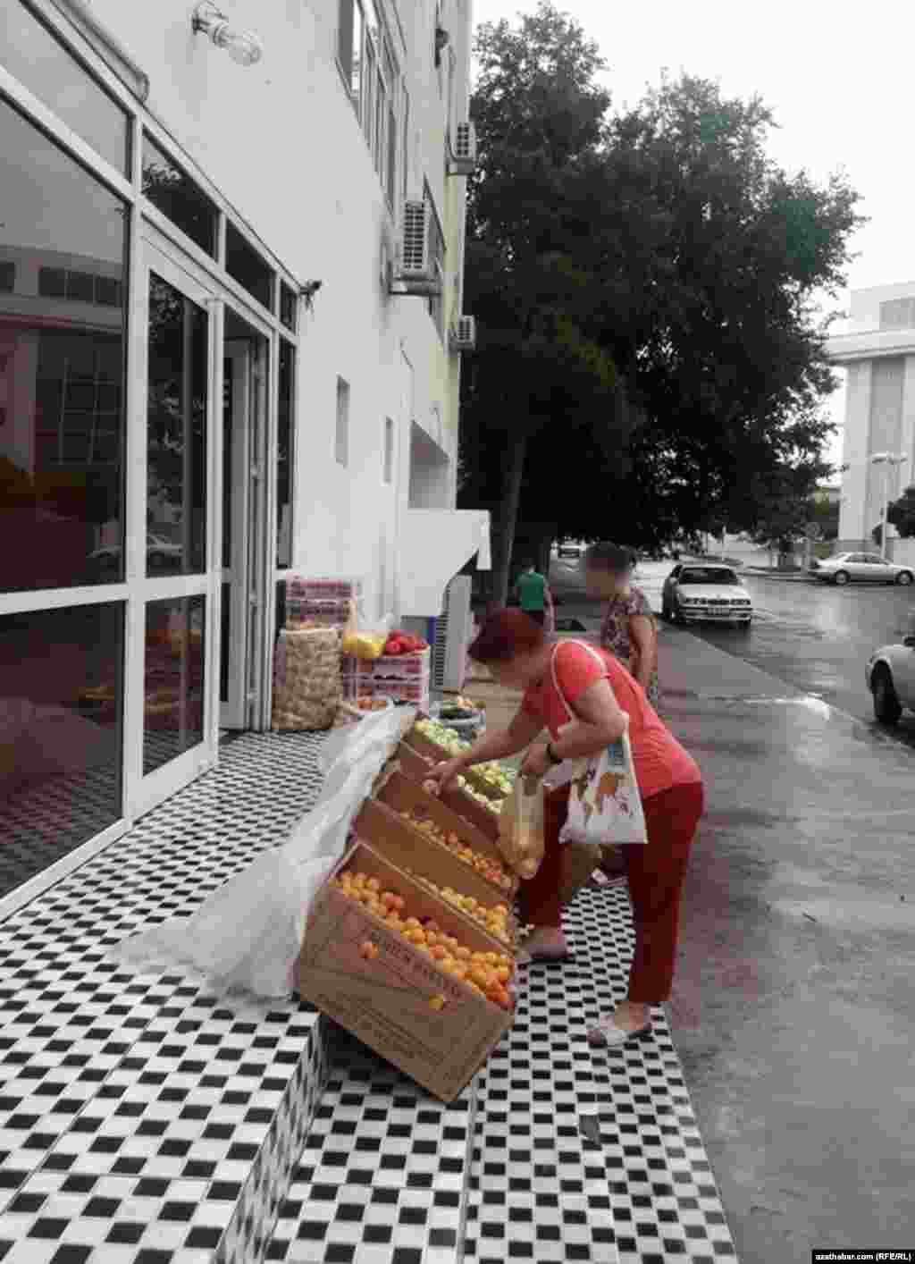 Aşgabat. Gök önüm dükanynda erik saýlaýan aýal. Iýun, 2020.