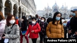 Italiýada gorag maskalaryny geýip köçä çykan syýahatçylar.
