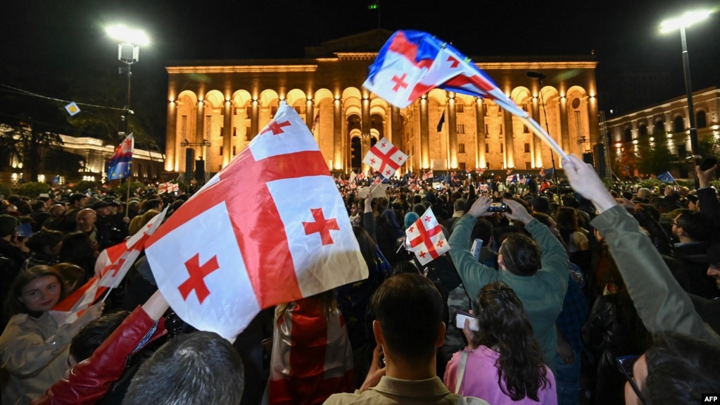 Хора развяват грузински знамена на протест срещу готвения законопроект за „чуждото влияние“ пред парламента в Тбилиси, 15 април 2024 г.