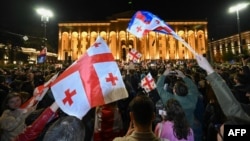 Хора развяват грузински знамена на протест срещу готвения законопроект за „чуждото влияние“ пред парламента в Тбилиси, 15 април 2024 г.