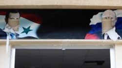 Испорченные портреты свергнутого сирийского президента Башара Асада и президента России Владимира Путина над входом в здание, которое использовалось российской армией, в сирийском городе Аль-Бассах, декабрь 2024 года
