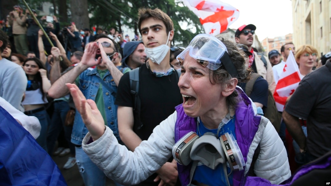 Un protestatar se ceartă cu ofițerii de poliție în timpul unui protest al opoziției împotriva legii „agentului străin” în fața clădirii parlamentului din Tbilisi, pe 28 mai.