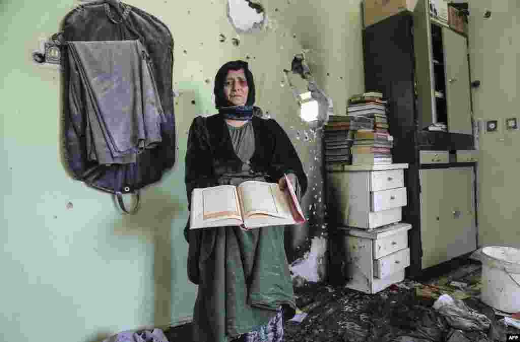 A Kurdish woman holds the Koran in a damaged house following clashes between Kurdish activists and Turkish government forces in Hakkari, Turkey. (AFP)