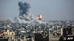 A ball of fire and a column of smoke erupts following Israeli bombardment of areas east of a neighborhood in eastern Gaza City on June 18. 