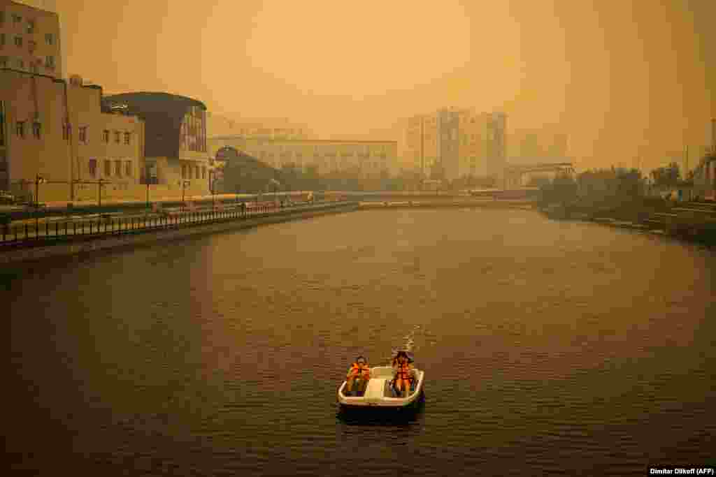 A couple rides a pedal boat as smoke from nearby forest fires hangs over the Russian city of Yakutsk.