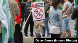 A young Romanian protester holds up an anti-LGBT sign at a rally ahead of the country's divisive upcoming referendum on the country's constitutional definition of marriage. 