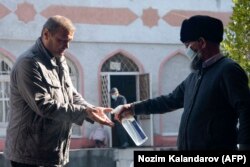 A man gets his hands disinfected as he enters a mosque in Dushanbe earlier this month. The public appears skeptical of official figures and accusations persist that the government is underreporting COVID-19 numbers.