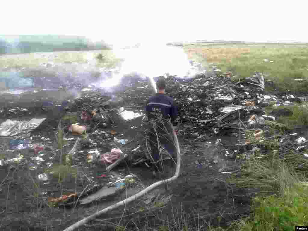 A man hoses down the burning wreckage of the Malaysia Airlines jet.